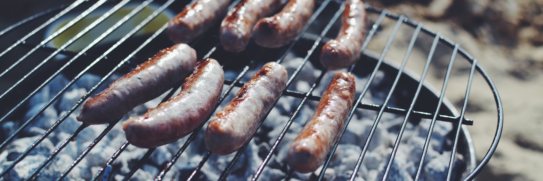 Sausages cooking on a charcoal grill